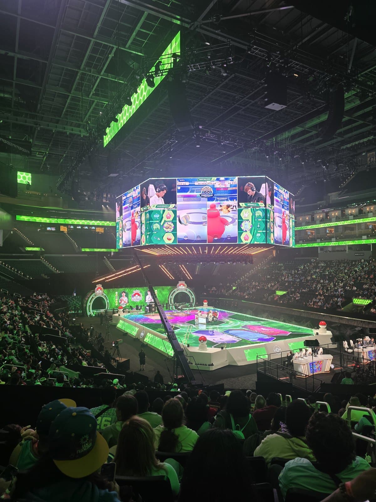 A large four sided screen above the arena floor showing the players and their cards