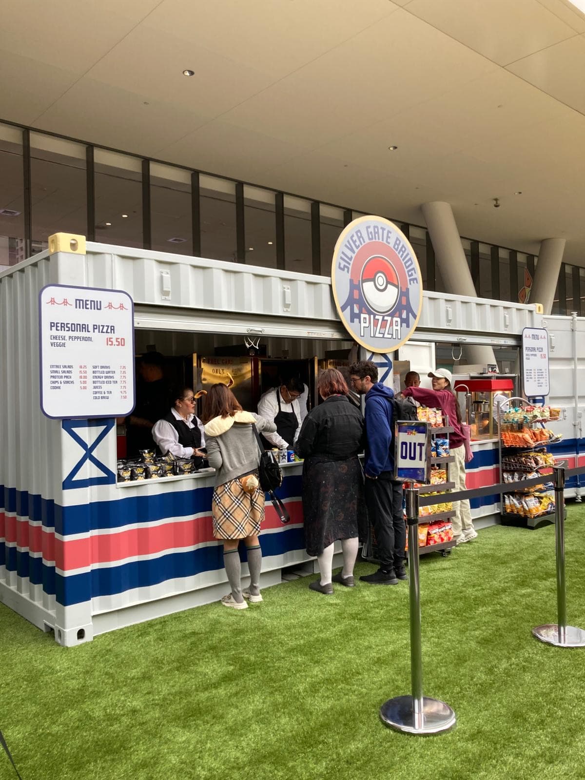 A food stall built to look like a shipping container, with a Golden Gate Pizza sign and a menu board