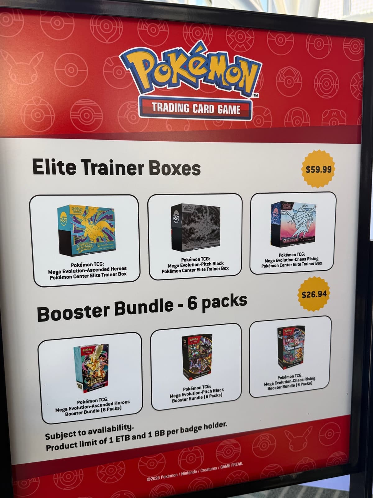 A price board showing Elite Trainer Boxes at 59.99 US dollars and six pack booster bundles at 26.94