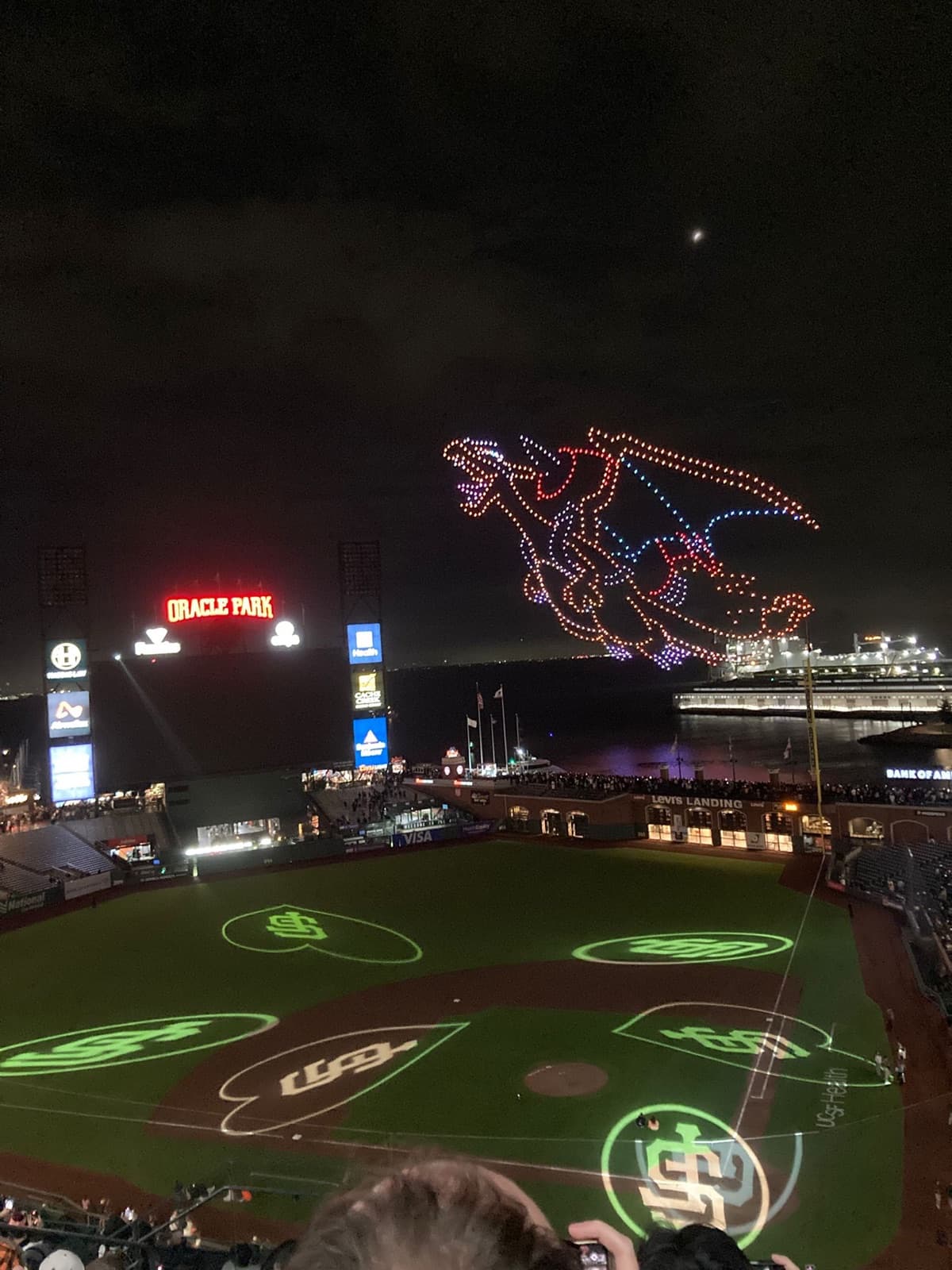 A drone display forming a Charizard in the night sky above a floodlit baseball stadium